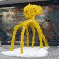 Stargate (installation, west) -- Public art installation of crayon yellow alien with 6 spiderlike legs, by #BlueRepublic (2016), 4.5 metres in height amongst smaller human-scale artifacts, has a blue counterpart blowing a horn across the street.  Around the midtown condominiums, the theme of inhabitants moving in and out inspired the artists who were emigrants from Poland.  Locale is a little farther from home than I would bike, especially on this cold but sunny day.  (Stargate art installation, 150 Redpath Avenue, Mountain Pleasant west neighbourhood, Toronto, Ontario) 20210221